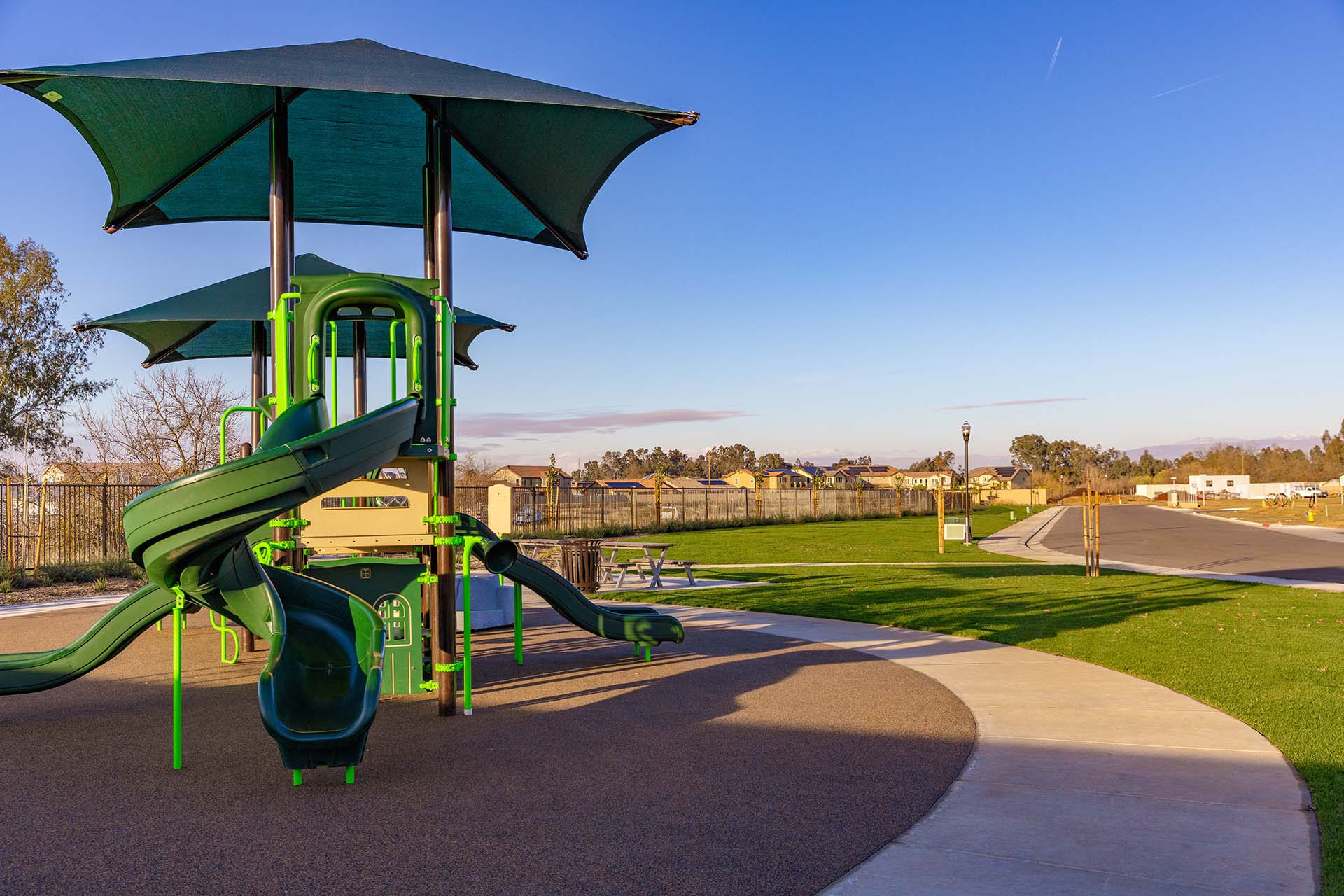 Vibrant green play structure nestled in the expansive Wisteria Creek park, offering endless fun and adventure for children of all ages.